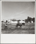 Plowing a field at Palmerdale, Alabama. New homestead in the background