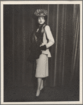 Fashion portrait of a woman in a fox stole, hat, and a suit dress with a waterfall hem on the jacket