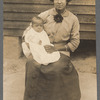 Portrait of a woman seated, holding a baby