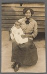 Portrait of a woman seated, holding a baby