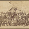 Group shot in front of Folies Bergère poster with Loie Fuller and large group of men 