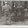 Men cleaning their boots after visit to stockyards. Denver, Colorado