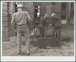 Men cleaning their boots after visit to stockyards. Denver, Colorado