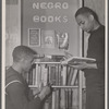 Two U.S. Navy sailors browsing library shelf labeled "Negro Books"