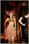 Model wearing Patrick Kelly Paris clothing, including large hat and bralette top designed to resemble watermelons, and printed skirt
