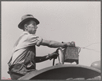 Hired hand tunes in radio on tractor while cutting hay. Kimberley farm, Jasper County, Iowa