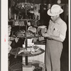 Farmer examines brushes for horses, cattle and hogs. Harness shop, Grundy Center, Iowa