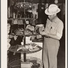 Farmer examines brushes for horses, cattle and hogs. Harness shop, Grundy Center, Iowa