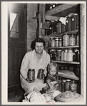 Mrs. Calvin Brown, wife of FSA (Farm Security Administration) borrower, and grandson with fruit preserved on their farm. Weld County, Colorado