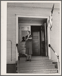 Lois Slinker, teacher of the one room school house. rings bell to end recess period. Grundy County, Iowa