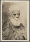 Photograph of man with beard in brimless hat and cloak