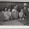 Woodville, California. FSA (Farm Security Administration) farm workers' community. Migrant agricultural workers eating hamburgers at the Saturday night dance