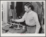 Tulare County, California. FSA (Farm Security Administration) farm workers' camp. Son of an agricultural worker making a model plane in the workshop