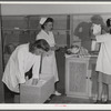 Eleven Mile Corner, AZ. FSA farm workers' community. Girls, who live at the NYA resident center learning baby care. The nurse, who divides her time between working at the hospital and instructing the NYA girls, is showing them how to care for a well baby