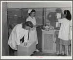 Eleven Mile Corner, AZ. FSA farm workers' community. Girls, who live at the NYA resident center learning baby care. The nurse, who divides her time between working at the hospital and instructing the NYA girls, is showing them how to care for a well baby