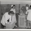 Eleven Mile Corner, AZ. FSA farm workers' community. Girls, who live at the NYA resident center learning baby care. The nurse, who divides her time between working at the hospital and instructing the NYA girls, is showing them how to care for a well baby