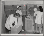 Eleven Mile Corner, AZ. FSA farm workers' community. Girls, who live at the NYA resident center learning baby care. The nurse, who divides her time between working at the hospital and instructing the NYA girls, is showing them how to care for a well baby