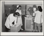 Eleven Mile Corner, AZ. FSA farm workers' community. Girls, who live at the NYA resident center learning baby care. The nurse, who divides her time between working at the hospital and instructing the NYA girls, is showing them how to care for a well baby