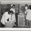 Eleven Mile Corner, AZ. FSA farm workers' community. Girls, who live at the NYA resident center learning baby care. The nurse, who divides her time between working at the hospital and instructing the NYA girls, is showing them how to care for a well baby