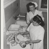 Eleven Mile Corner, AZ. FSA farm workers' community. Girls, who live at the NYA resident center learning baby care. The nurse, who divides her time between working at the hospital and instructing the NYA girls, is showing them how to care for a well baby