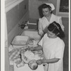 Eleven Mile Corner, AZ. FSA farm workers' community. Girls, who live at the NYA resident center learning baby care. The nurse, who divides her time between working at the hospital and instructing the NYA girls, is showing them how to care for a well baby