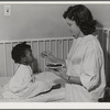 NYA (National Youth Association) girl feeds lunch to little girl who is a patient at the Cairns General Hospital located at the FSA (Farm Security Administration) farm workers' community at Eleven Mile Corner, Arizona