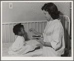 NYA (National Youth Association) girl feeds lunch to little girl who is a patient at the Cairns General Hospital located at the FSA (Farm Security Administration) farm workers' community at Eleven Mile Corner, Arizona