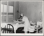 Eleven Mile Corner, Arizona. Cairns General Hospital, FSA (Farm Security Administration) farm workers' community. Nurse removing bandages from a patient