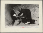 Spanish-American woman putting loaf of bread into oven, Taos County, New Mexico