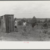 FSA (Farm Security Administration) home management supervisor pointing out to rehabilitation borrower where new privy will be located. Greene County, Georgia