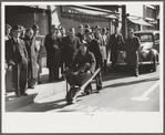 Tobacco auctioneer who "bet on Carolina" and lost, pays off the wager by pushing the warehouseman in a wheelbarrow from the warehouse to the courthouse. Durham, North Carolina