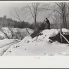 Hired man on Gilbert farm emptying load of manure after cleaning out the dairy barn early on a winter morning. Woodstock, Vermont