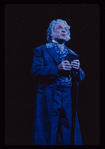George Rose [raising book]  in the stage production The Mystery of Edwin Drood