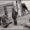 Baldwin kneeling with shades between two children, Louisiana, 1963