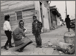 Baldwin kneeling with shades between two children, Louisiana, 1963