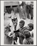 Baldwin showing small book to children, Louisiana, 1963