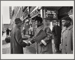 Baldwin shaking hands with man by Apollo Theater