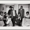 Baldwin standing in kitchen with extended family, smiling at three girls