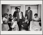 Baldwin standing in kitchen with extended family, smiling at three girls