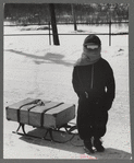 Child bringing home suitcase on sled, Franconia, New Hampshire