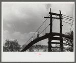 Mountaineers crossing the Kentucky River over swinging bridge, carrying their supplies home from Jackson. Breathitt County, Kentucky
