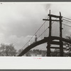 Mountaineers crossing the Kentucky River over swinging bridge, carrying their supplies home from Jackson. Breathitt County, Kentucky