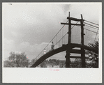 Mountaineers crossing the Kentucky River over swinging bridge, carrying their supplies home from Jackson. Breathitt County, Kentucky