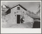 Mrs. S. Castle or Mrs. William S. Allen with canned goods in front of new storage house her husband built on their farm with FSA (Farm Security Administration) help. Southern Appalachian project, near Barbourville, Knox County, Kentucky