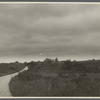 View of road with big house and windmill in the distance. Shinnecock Hills, Southampton