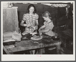 Woman migrant packinghouse worker and her oldest child fixing supper. She has three other children. Belle Glade, Florida