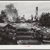 Farm wagehand (day laborer, seventy-five cents per day) and his young wife looking at remains of their home (on three acre piece of land owned by his mother) which had just burned to the ground. Greene County, Georgia