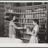 Mrs. Peacock and daughter Mary, RR (Rural Rehabilitation) four years, getting some of their supply of canned foods for dinner. Many families keep their jars on shelves along wall in bedroom and living room. Coffee County, Alabama