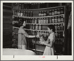 Mrs. Peacock and daughter Mary, RR (Rural Rehabilitation) four years, getting some of their supply of canned foods for dinner. Many families keep their jars on shelves along wall in bedroom and living room. Coffee County, Alabama