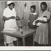 Nurse Shamburg demonstrates care of baby bottles to Mrs. Paralee Coleman and Marie. Mothers have to work in field and children are left at home to care for babies. Health clinic, Gee's Bend, Alabama